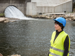 Dam and turbines of a hydroelectric power station with falling water flows and woman worker
