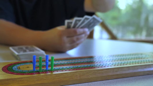 Close up of someone advancing a peg on a cribbage board.