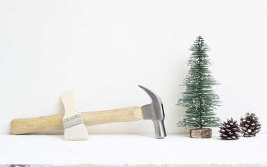 Merry christmas and Happy New year with handy tools background concept, hammers and paintbrush with Christmas tree and pine cones decoration on wood with copy space.