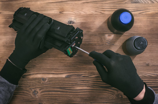 Computer technician engineer is refilling a laser toner cartridge. Office equipment maintenance concept.
