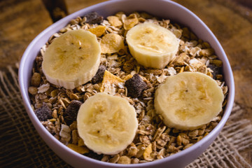 Bowl of cereal with fruit, pieces of banana with oats and cereal.