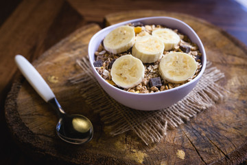 Bowl of cereal with fruit, pieces of banana with oats and cereal.