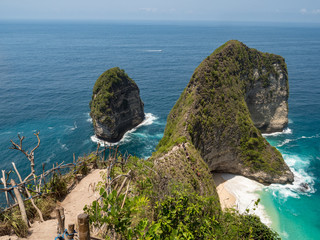 Amazing view of a Kelingking beach located in Nusa Penida, southeast of Bali Island, Indonesia. Wonderful seashore cliffs meet the great blue and turquoise ocean in a sunny blue sky. October, 2018