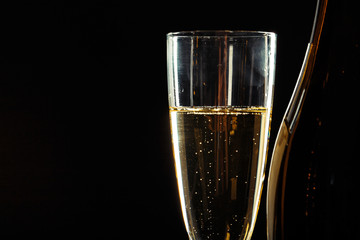 bottle of champagne and glasses over dark background