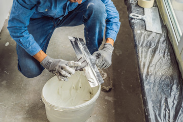 master is applying white putty on a wall and smearing by putty knife in a room of renovating house...