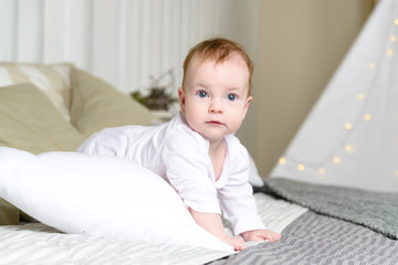 Fototapeta premium Baby girl in white bodysuit on the bed
