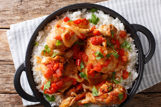Haitian chicken in a spicy tomato sauce with rice side dish close-up in a pan. horizontal top view