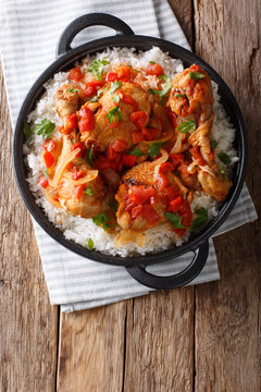 Haitian Stewed Chicken (Poule en Sauce)served with white rice in a black pan closeup. Vertical top view