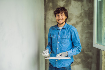 master is applying white putty on a wall and smearing by putty knife in a room of renovating house...