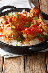 Haitian chicken in a spicy tomato sauce with rice side dish close-up in a pan. vertical