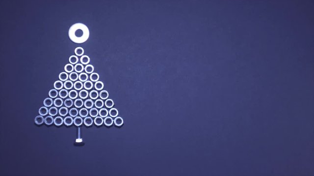Time Lapse. Iron Christmas tree of bolts and nuts on a plain background