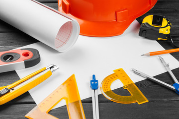 Close up orange hardhat and variety of repair tools with copy space in the middle over wooden  background