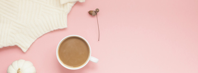 Cup of coffee and white sweater on pink background