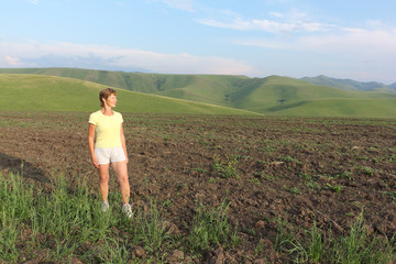 Woman in a yellow T-shirt standing on a mountain field in summer, Altai territory, Russia