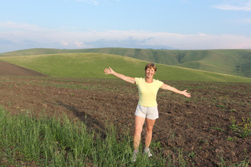 Woman in a yellow T-shirt standing on a mountain field in summer, Altai territory, Russia