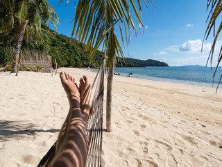 Man relaxing in the hammock on tropical beach with palm-trees, hot sunny day. Philippines, November, 2018 © ikmerc