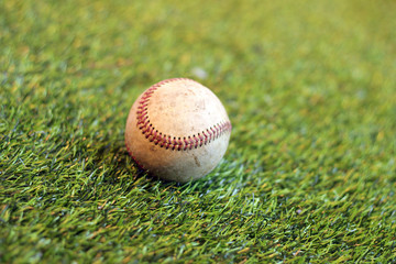 Old baseball on grass background