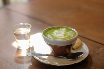 hot matcha green tea with leaves latte art on wood table