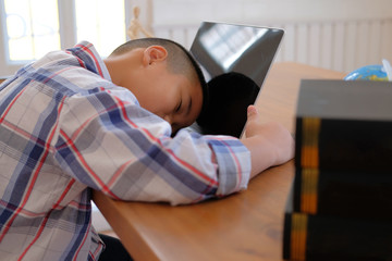 lazy stressed young little asian kid boy  resting sleeping on desk. child fall asleep. children tired from studying in classroom.