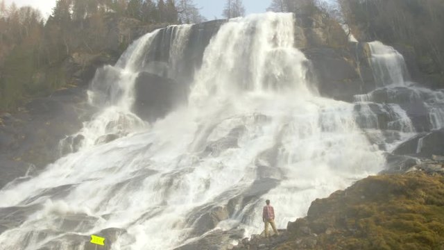 A Hiker Enjoys the Incredible View of the Furebergfossen Waterfall in Norway