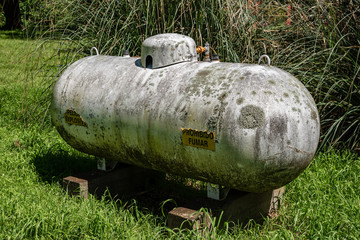 Old and moldy rusty white industrial propane gas tank