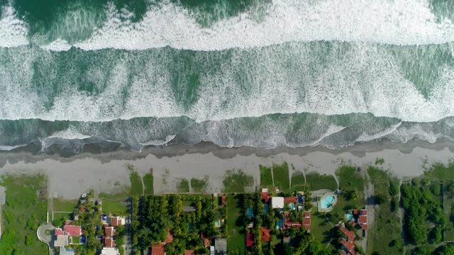 Fixed shot over a tropical coast showing beach houses- Fixed drone shot of the swell beetwen the beach 
