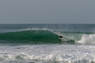 Surfer on Atlantic ocean wave , Nazare , Portugal.