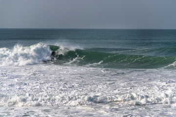 Surfer on Atlantic ocean wave , Nazare , Portugal.
