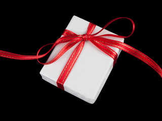White gift box with red bow on black background