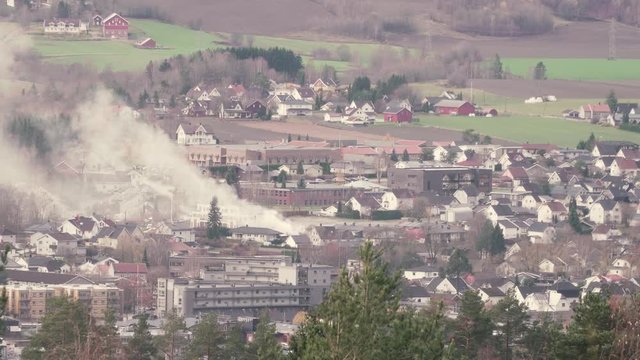 A fire is burning in the center of the town of Mj&radic;&prod;ndalen in Norway.  Shot from high ground. Lots of smoke is visible.
