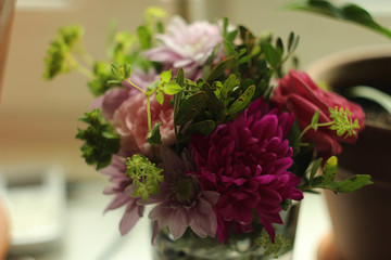 bouquet of lilac and pink flowers with green small leaves in a transparent glass