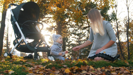 Young mother with her excited little baby in autumn park