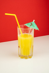 Orange cocktail drink on white and red background.  Image of citrus juice glass at bright minimalistic environment.