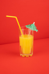 Orange cocktail drink on red background.  Image of citrus juice glass at bright minimalistic environment.