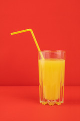 Orange cocktail drink on red background.  Image of citrus juice glass at bright minimalistic environment.