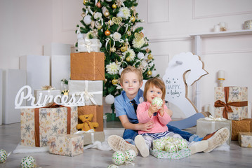 Boy and girl in the studio with a Christmas interior. Little Brother and Sister at Christmas. Waiting for children to give presents
