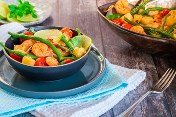 Thai prawns with pineapple and green beans on rustic wooden table