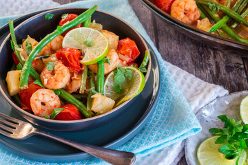 Thai prawns with pineapple and green beans on rustic wooden table