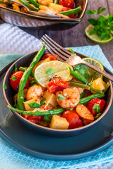 Thai prawns with pineapple and green beans on rustic wooden table