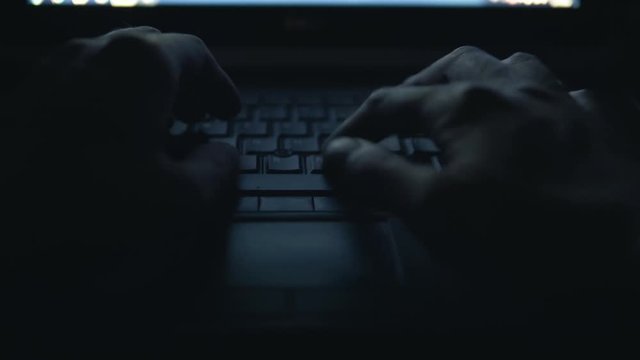 Hacker Typing Code on Laptop in the Dark