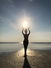 silhouette of woman at the seaside supporting the sun with her hands