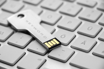 Silver USB stick on keyboard -caption keyword