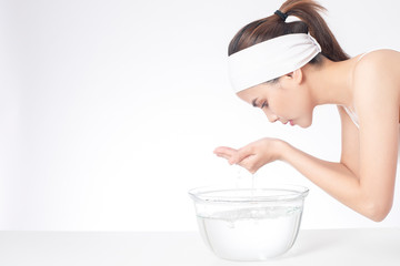 Beautiful woman is washing her face on white background