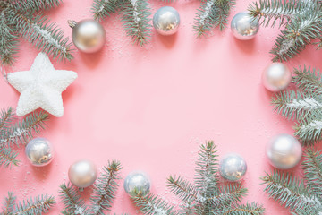 Christmas frame made of fir branches, snowy white decorations,white star balls on pink table. Xmas background. Flat lay. Top view with copy space