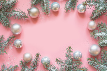 Fototapeta na wymiar Christmas frame made of fir branches, white balls on pink. Xmas. Flat lay. Top view with copy space