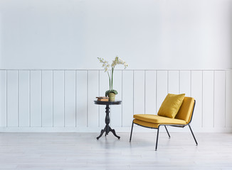 Modern yellow chair with pillow and black coffee table vase of plant.