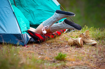 Woman traveler resting in a tent against the background of a green forest