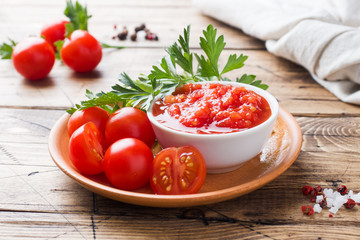 Tomato sauce pasta in a bowl and fresh tomatoes with parsley on a wooden table