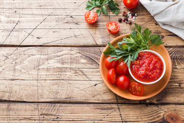 Tomato sauce pasta in a bowl and fresh tomatoes with parsley on a wooden table Copy space