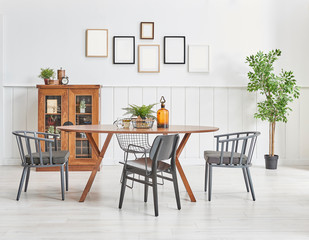 Dining room style with wooden furniture table cabinet and chair style. Many frame on the wall with vase of plant.